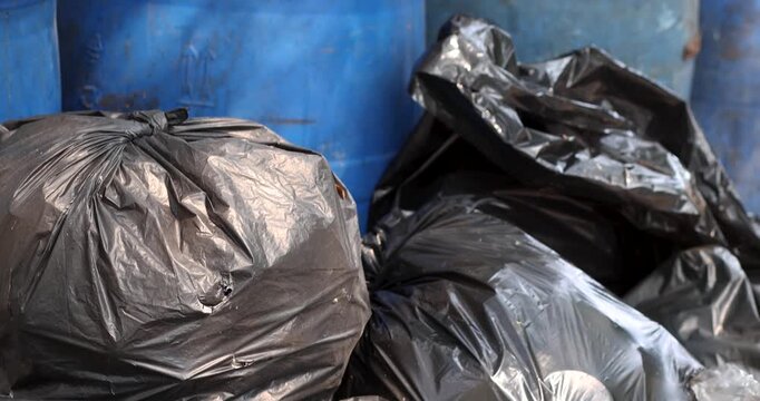 Pile of black garbage bags plastic at a bin, Garbage pile, Plastic waste, Pollution, and urban waste management issues