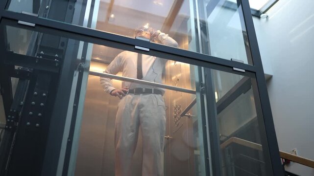 Startup founder shouting on headset in elevator after failed deal feeling intense stress frustration and anger losing control reacting emotionally to business setback
