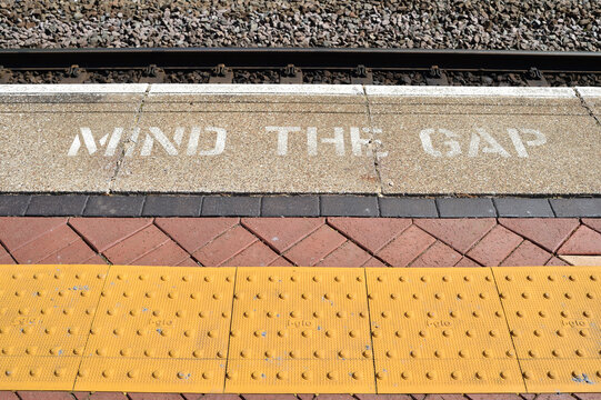Mind the Gap warning text painted o0n side of Train station platform