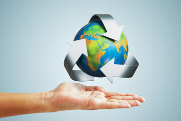 Recycling concept with globe and arrows above human hand on light background illustrating environmental responsibility and sustainability.