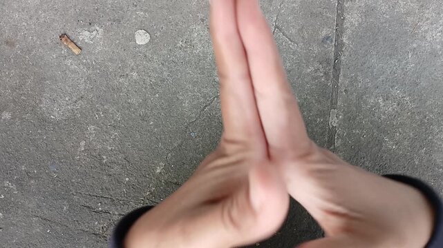 A woman's hands are folded, pressing her fingers until they make a "kretek" sound to feel the tension.