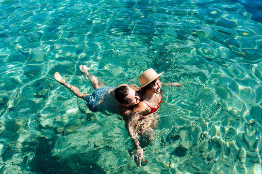 Romantic couple embracing in turquoise sea water during summer vacation top view.