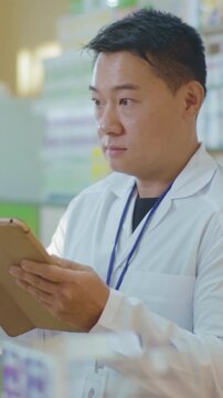 Pharmacist reviewing inventory, Dedicated pharmacist in white coat assesses digital drug records attentively
