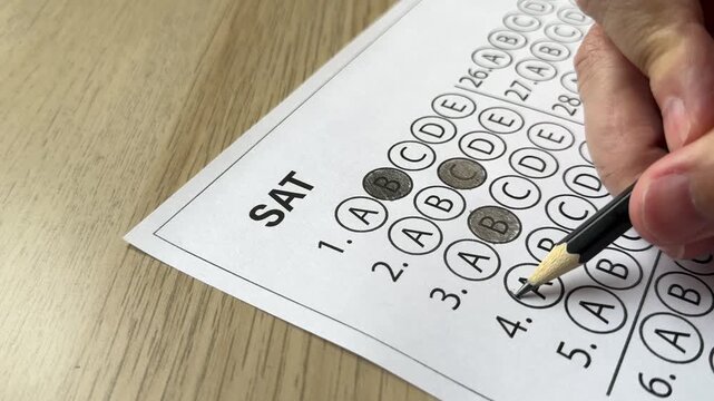 Hand marking answers on multiple choice exam sheet. Concept of test taking, exam practice and academic preparation