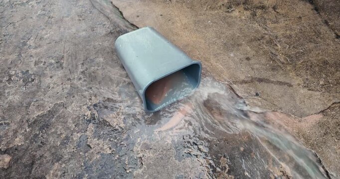 close up of a grey plastic bin in a flash flood. Turbulent muddy water rushes into the container on rough concrete, capturing authentic fluid dynamics, eddies, and splashes in an urban environment