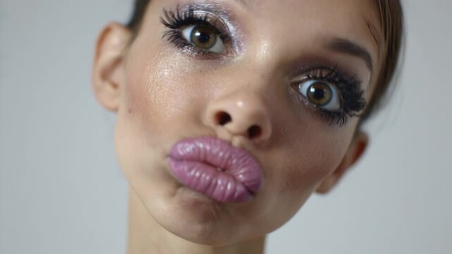 Close-up of a beautiful model with dramatic makeup puckering her lips and sending an air kiss