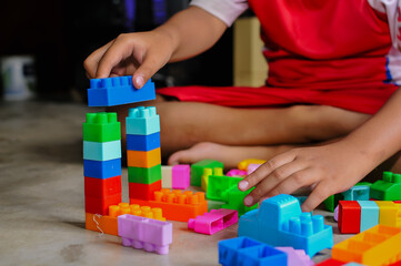 Fototapeta premium Close-up of a child’s hands playing with colorful building blocks (LEGO-style toys). The image highlights creativity, learning through play, and fine motor skill development in early childhood
