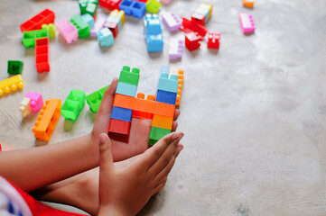 Fototapeta premium Close-up of a child’s hands playing with colorful building blocks (LEGO-style toys). The image highlights creativity, learning through play, and fine motor skill development in early childhood. Bright