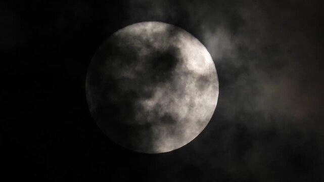 A full moon partially obscured by passing clouds