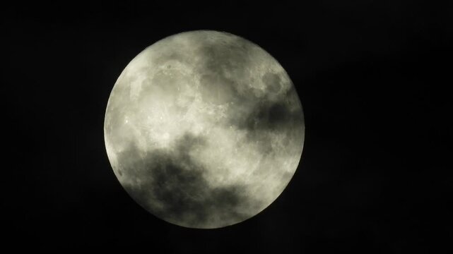 a full moon partially obscured by passing clouds