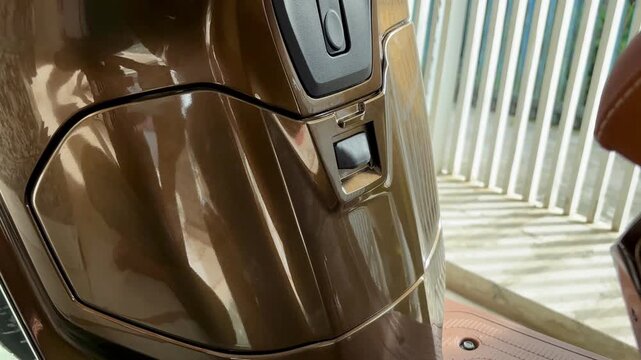 Video of an Asian woman closing the storage compartment of a brown scooter with a practical design for urban transportation.