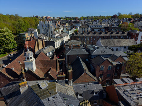 Above Tunbridge Wells town. Closeup aerial view of old town. Anglican church bell tower and roofs of residential houses. View towards the High street and the green hill. Quiet sunny day in springtime.