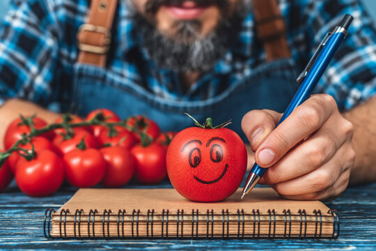 Man drawing smile on tomato with pen creative food concept