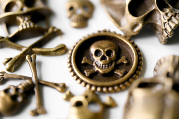 Macro shot of antique gold pirate coins and skull symbols scattered on a white surface. Spooky vintage composition perfect for Halloween decorations and death concepts. Photo © slexp880
