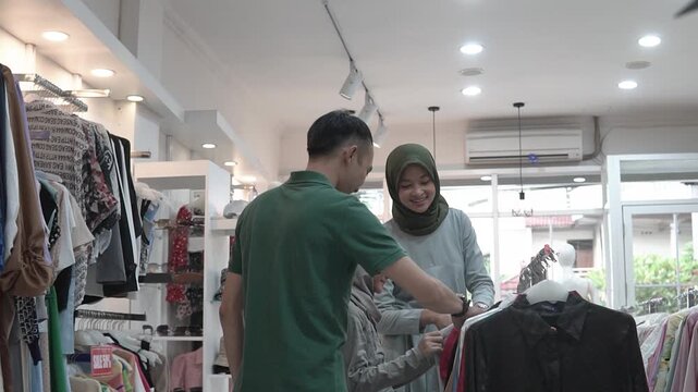 Man woman browsing clothes rack smiling, trio discussing outfits and price tags, friendly staff guidance, bright boutique