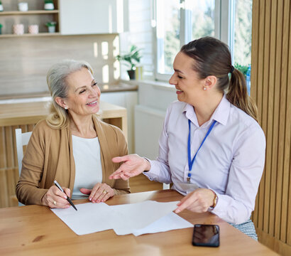 Happy senior old woman or busiesswoman clients make financial insurance estate business deal contract signing, agent lawyer, satisfied mature customers signing contract meeting bank manager businesswo