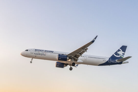 Phuket Thailand 30.11. 2025: Qanot Sharq Airbus A321 passenger airplane landing with landing gear down against clear blue sky, Uzbek airline commercial aviation and air transport concept