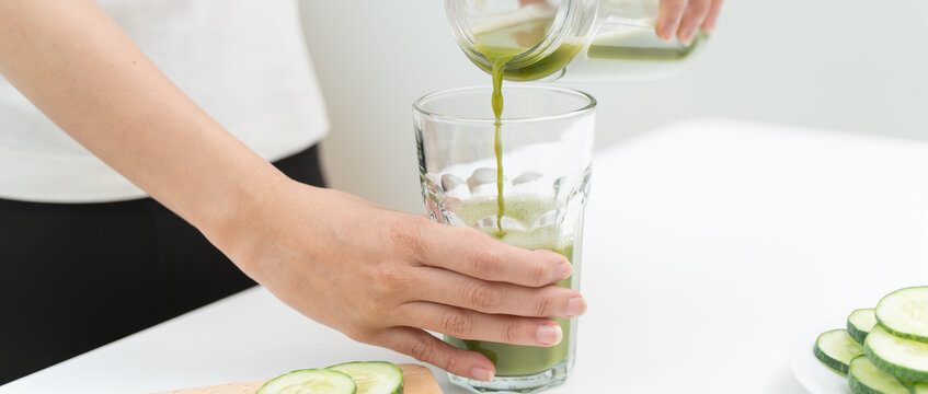 Detox juice concept, Hand of woman, girl holding bottle making green vegetable smoothie pouring in glass for diet at home kitchen, drinking healthy meal food for weight loss. Lifestyle vegan nutrition