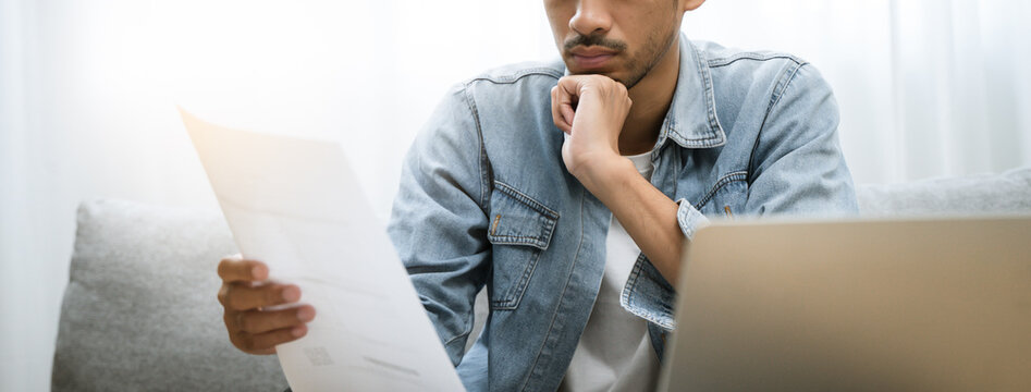 Household financial economic concept, Stressed Young Asian adults are looking at credit card bills issued documents, and apartment loan mortgages and worrying about having no money to pay.
