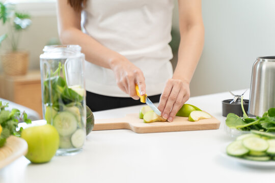 Woman putting fruit and vegetable into blender to make detox healthy drink.