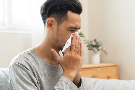 Seasonal cold sickness in people concept, Sick asian man looking at thermometer during measuring his body temperature feel exhausted and headache from fever.