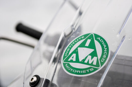 Close up view of a green Institute of Advanced Motorists IAM badge sticker attached to the clear windscreen of a Honda motorcycle