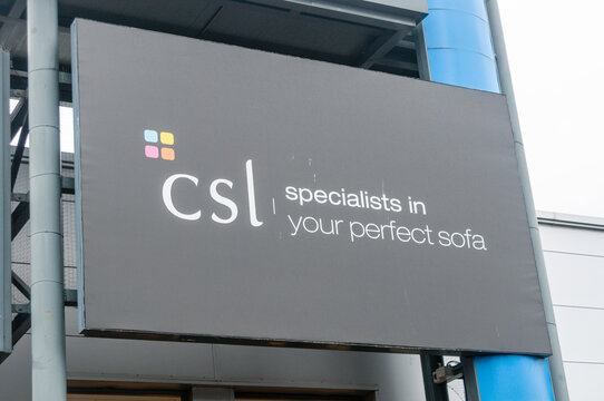 A branded sign marking the entrance to a CSL furniture store, showcasing the company's iconic logo at a modern retail park