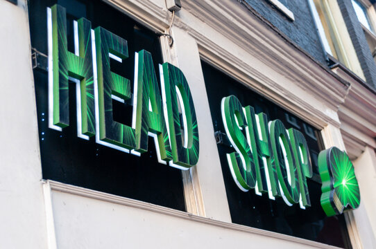 Exterior signage of a shop selling smoking accessories, herbal products, and various lifestyle items, previously known for stocking legal high substances, on a city street in Northern Ireland.