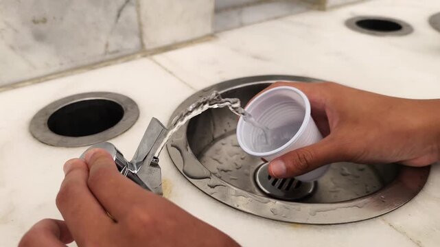 Filling a white plastic cup with refreshing zamzam water