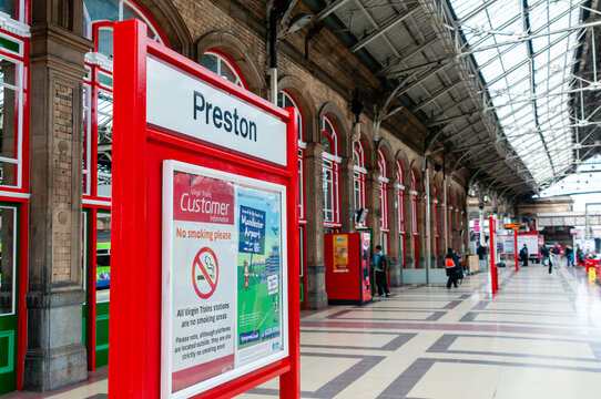 An empty platform at Preston railway station, featuring modern architecture and steel structures, captured in a quiet and tranquil atmosphere with only a few passengers in view.