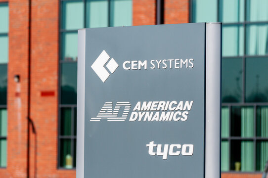 A crisp, professional sign featuring the branding for CEM Systems, American Dynamics, and Tyco mounted on a modern building facade, identifying the headquarters of these technology companies.