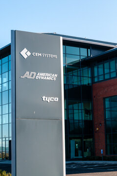 A crisp, professional sign featuring the branding for CEM Systems, American Dynamics, and Tyco mounted on a modern building facade, identifying the headquarters of these technology companies.