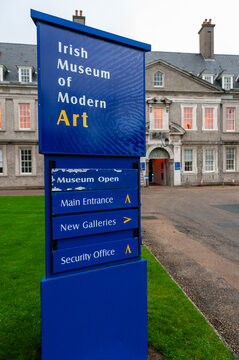 Sign at the entrance to the Irish Museum of Modern Art in Kilmainham, Dublin, set against the historic stone facade of the former Royal Hospital building and its sprawling green lawns.