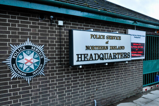 Daytime exterior shot of the official entrance signage at the PSNI Knock Headquarters in Belfast, featuring the Police Service of Northern Ireland emblem on a secure perimeter wall.