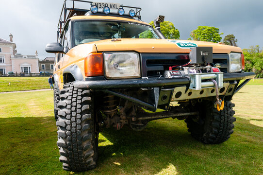 A rugged yellow Land Rover Defender 4x4 navigating challenging off-road terrain, showcasing its high ground clearance and all-terrain capabilities during an adventurous cross-country expedition.