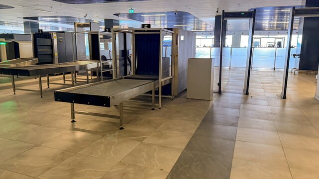 Empty airport security checkpoint with metal detectors and conveyor tables, clean modern terminal interior, quiet orderly mood for travel and safety