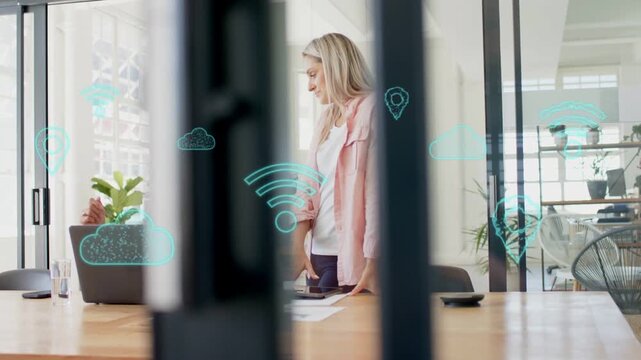 Two women in IT, standing woman pointing phone, papers, reviewing laptop, teal icons floating