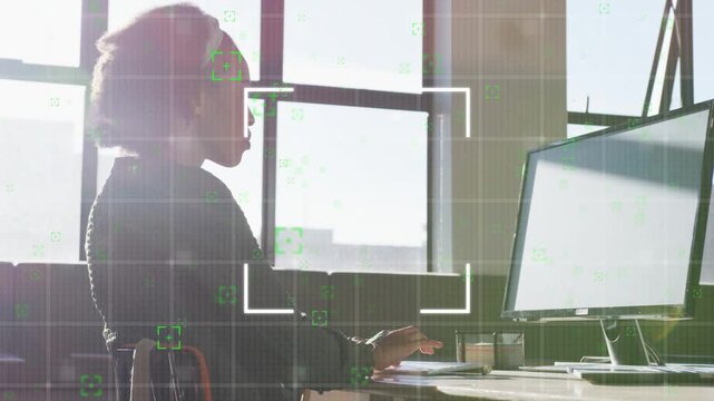 Woman working at office desk, moving hand to mouse and typing, overlay focus grid revealing face