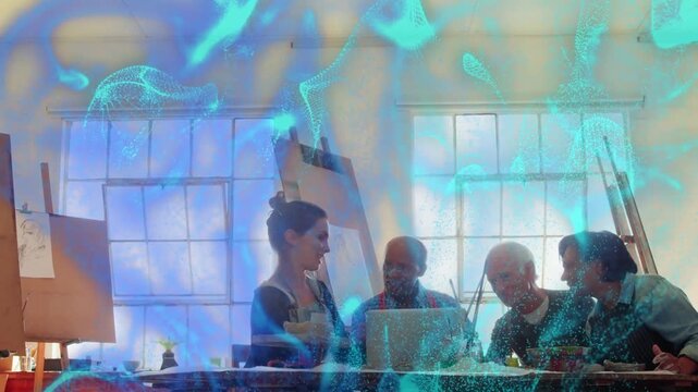 Standing mentor gesturing at laptop, group working in art studio causing blue overlay showing ideas