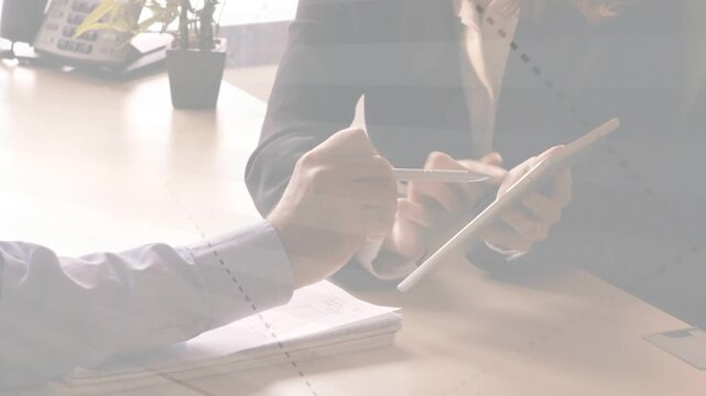 Man pointing pen and animating chart from tablet, woman tapping tablet, man writing business notes