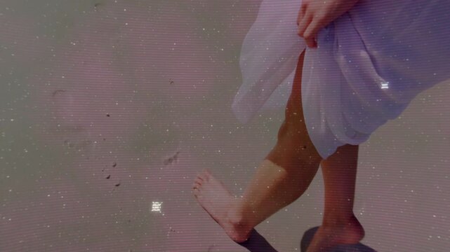 Female walking sand, right step starting, HUD popping, fading, hand holding hem to keep clean