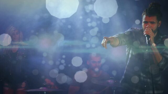 Arm cueing lead vocalist moving center holding mic singing to engage music fans, bokeh over lead