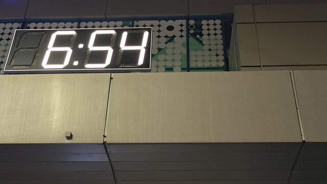Digital clock display shows changing time and temperature readings in a modern urban setting, highlighting the transition from -4C to 6:54 and back to -4C