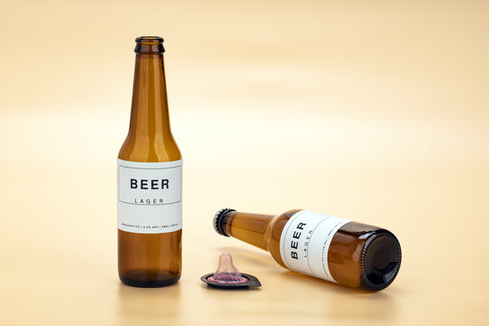 Amber beer lager bottles beside an unrolled pink condom on a warm pastel yellow background, representing safe sex awareness and the risks of alcohol and sexual decision-making
