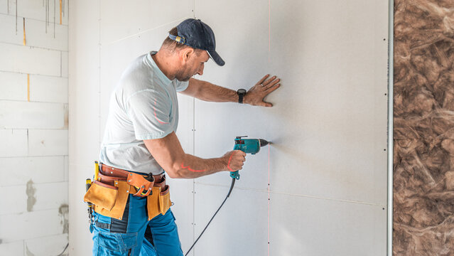 Making a plasterboard partition. A drywaller using an electric quick screwdriver for plasterboard fixing.