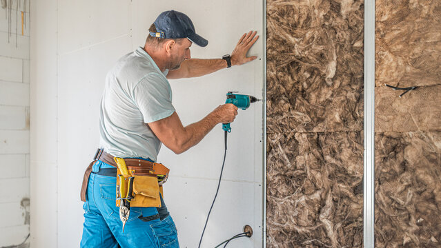 Making a plasterboard partition. A drywaller using an electric quick screwdriver for plasterboard fixing.