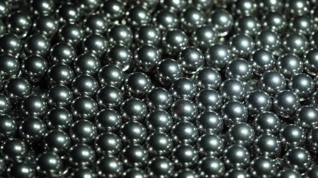 closeup black metal steel spheres in a tight pattern. These shiny dark beads create a luxury texture with elegant reflections abstract background rotation turntable video footage