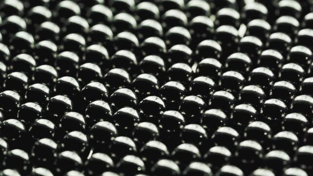 closeup black metal steel spheres in a tight pattern. These shiny dark beads create a luxury texture with elegant reflections abstract background rotation turntable video footage
