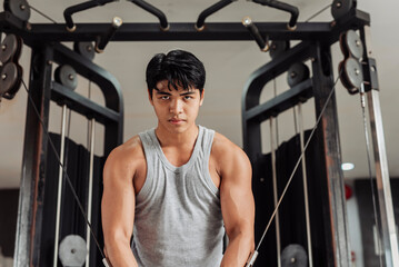 Young Asian man does cable crossover at the gym, holding peak contraction to highlight chest muscle definition and controlled resistance technique. © Mdv Edwards