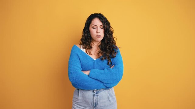Unhappy and resentful woman with curly hair standing with arms crossed. Her facial expression showing disappointment and discontent